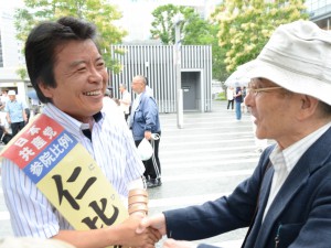 第一声を聞いた聴衆と握手する仁比候補（左）＝7月4日、博多駅前